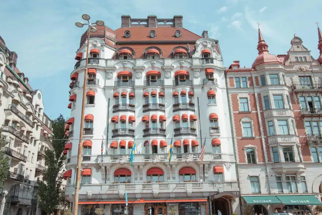 Weiße Jugendstilfassade mit roten Markisen und Flaggen in Stockholm