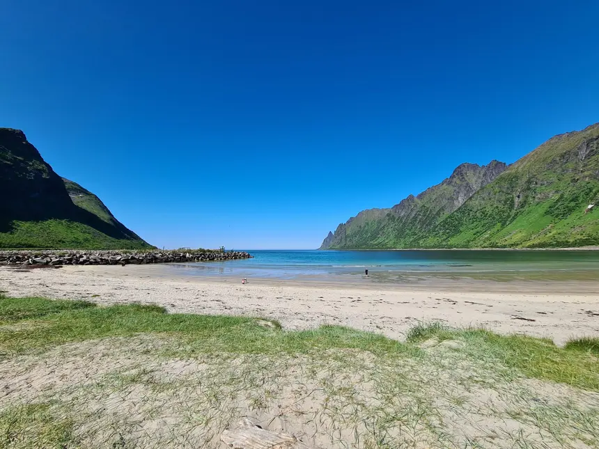 Heller Sandstrand der Ersfjordstranda mit türkisblauem Wasser und grünen Berghängen