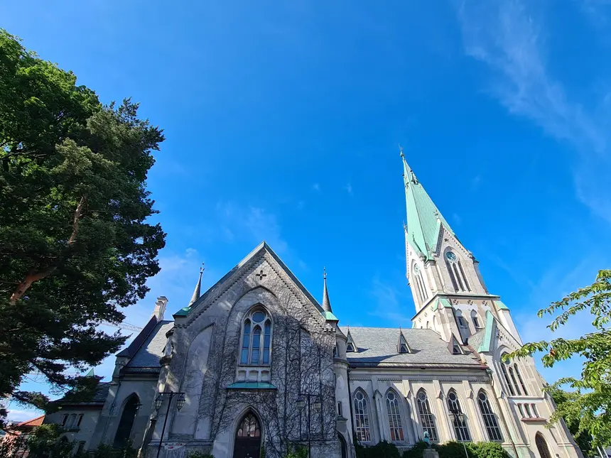 Dom von Kristiansand mit grünem Turmspitzdach vor strahlend blauem Himmel