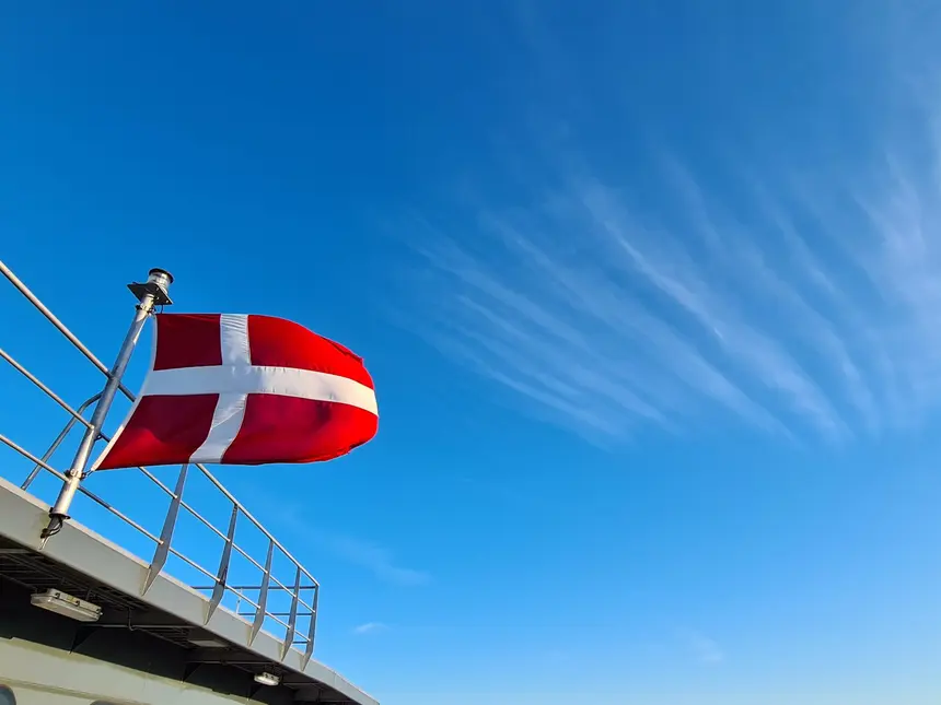 Dänische Flagge weht am Heck der Fähre vor blauem Himmel
