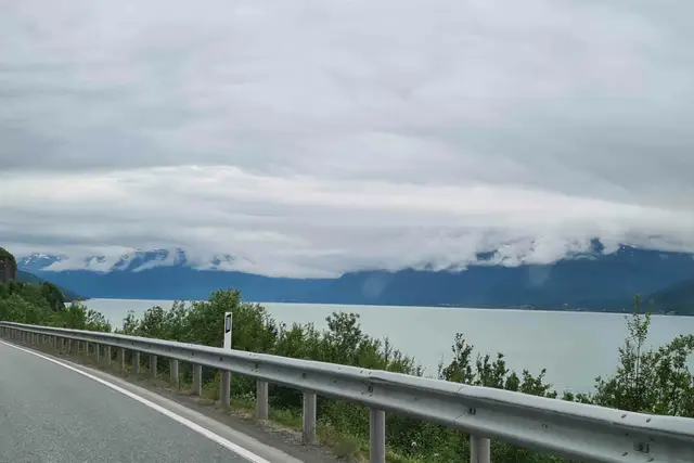 Küstenstraße am Fjord auf dem Weg nach Tromsø, Wolken hängen tief über den Bergen