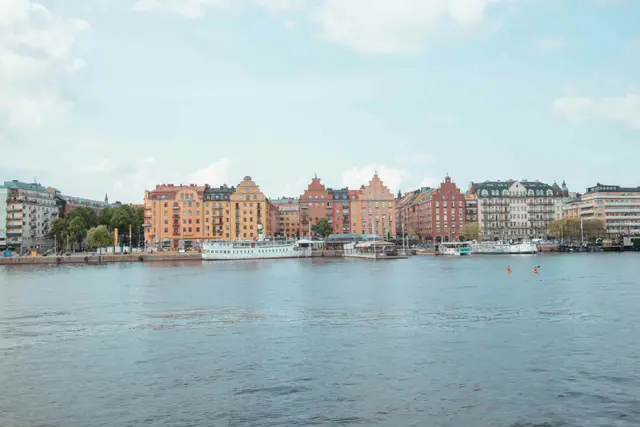 Bunte Uferzeile mit Ausflugsbooten in Stockholm, davor zwei Kajaks auf dem Wasser