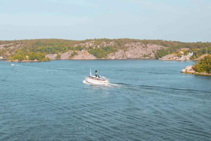 Weißes Dampferschiff zieht durch die bewaldete Schärenlandschaft vor Stockholm