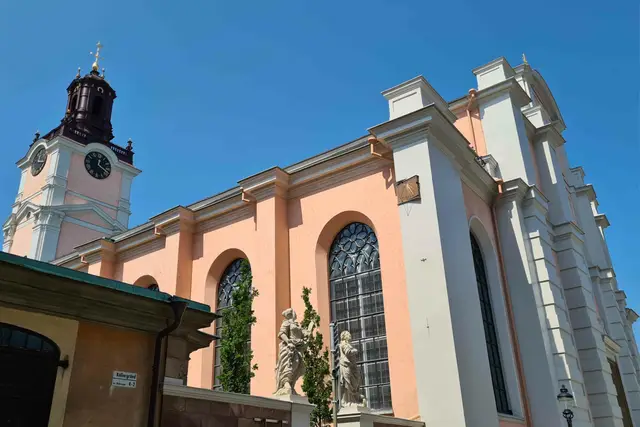 Fassade der Storkyrkan mit Uhrturm und Steinfiguren unter blauem Himmel