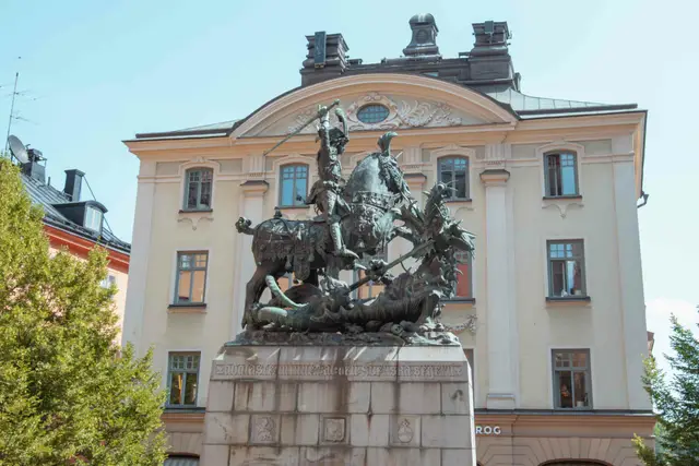 Bronzestatue des heiligen Georg im Kampf mit dem Drachen vor barocker Hausfassade