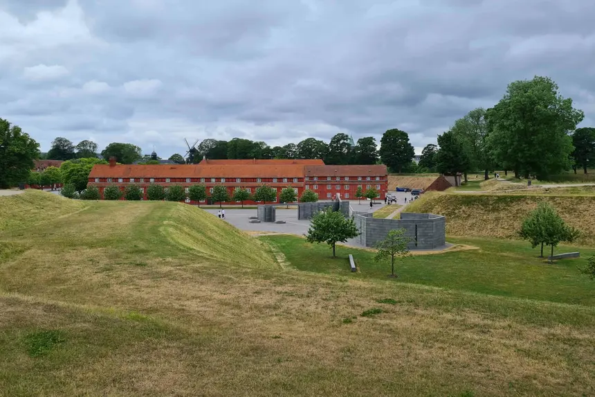 Rote Kasernenzeile des Kastellet mit grünen Wallanlagen und Windmühle im Hintergrund