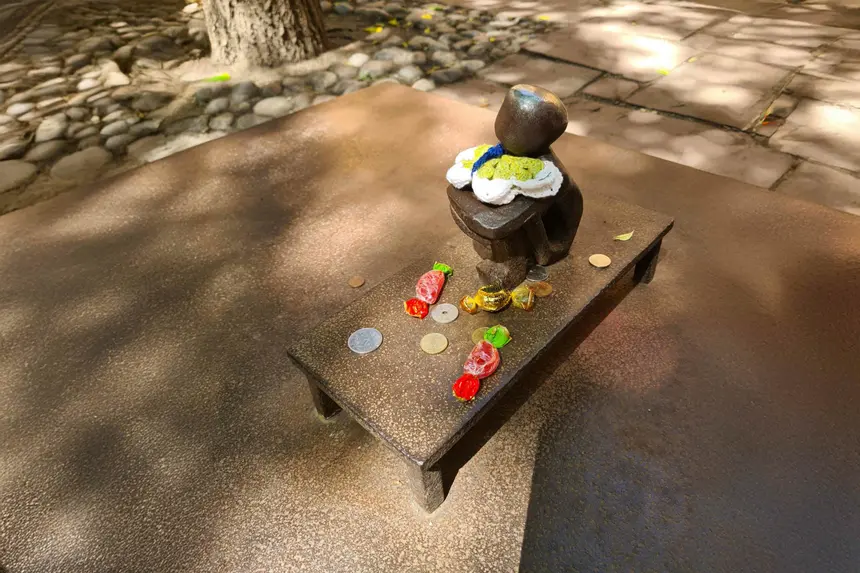 Winzige Iron-Boy-Statue mit gestrickter Mütze, umgeben von Münzen und Bonbons