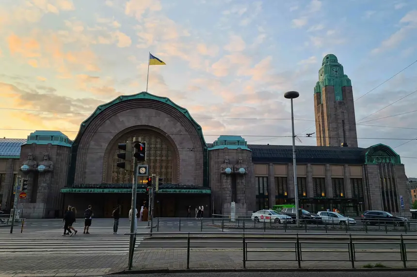 Hauptbahnhof Helsinki mit Lampenträger-Statuen und Uhrturm im Abendlicht