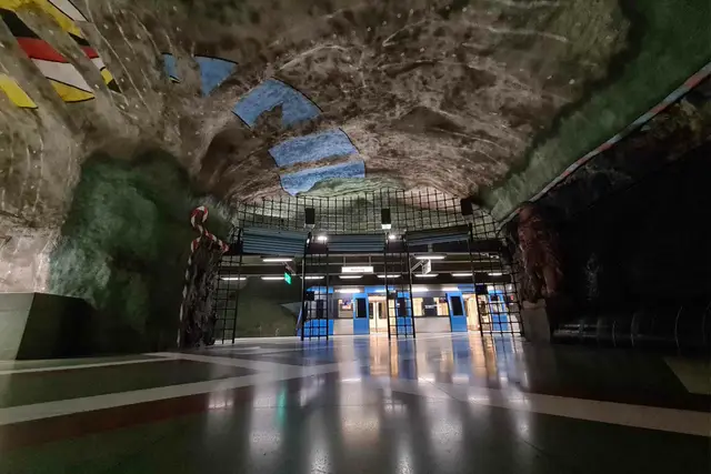 Blauer Zug hält in der höhlenartigen, bemalten Station Kungsträdgården