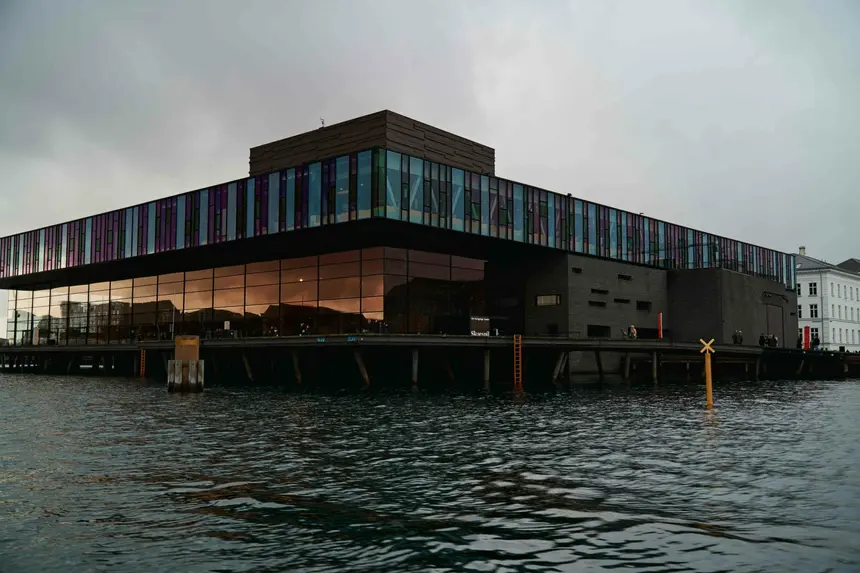 Skuespilhuset am Wasser mit farbig schimmerndem Glasband in der Abenddämmerung