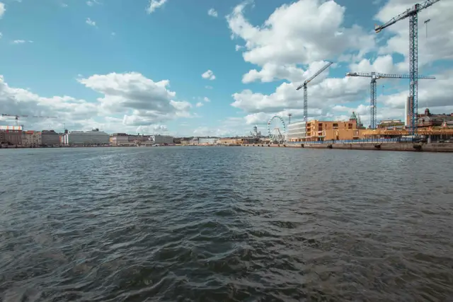 Blick von der Fähre auf Helsinkis Hafenfront mit Dom, Riesenrad und Kränen