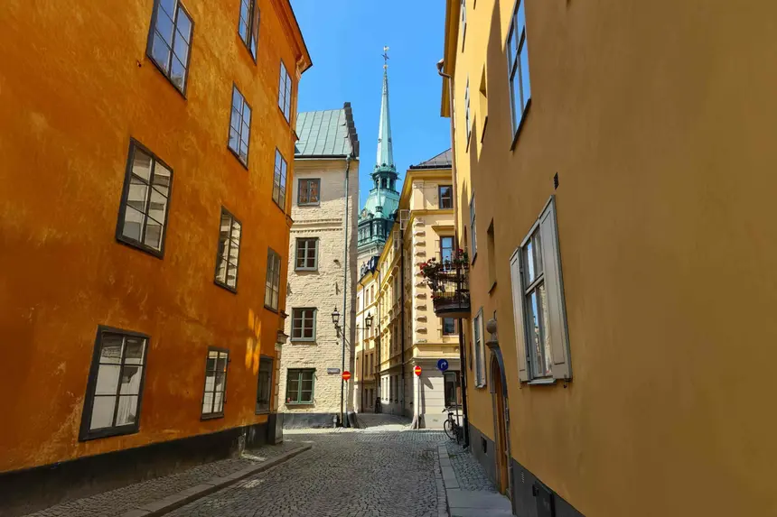 Grüne Turmspitze der Tyska Kyrkan über einer Kopfsteinpflastergasse in Gamla Stan
