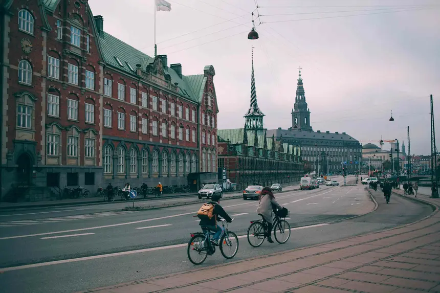 Drehender Drachenschwanz-Turm der Børsen und Christiansborg hinter Radfahrern auf dem Boulevard