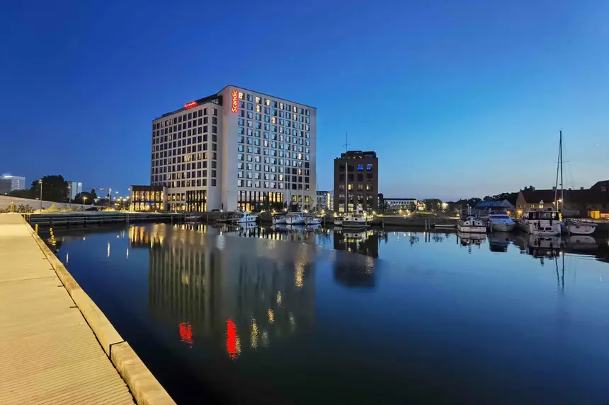 Beleuchtetes Scandic-Hotel spiegelt sich zur blauen Stunde im Kopenhagener Hafenbecken
