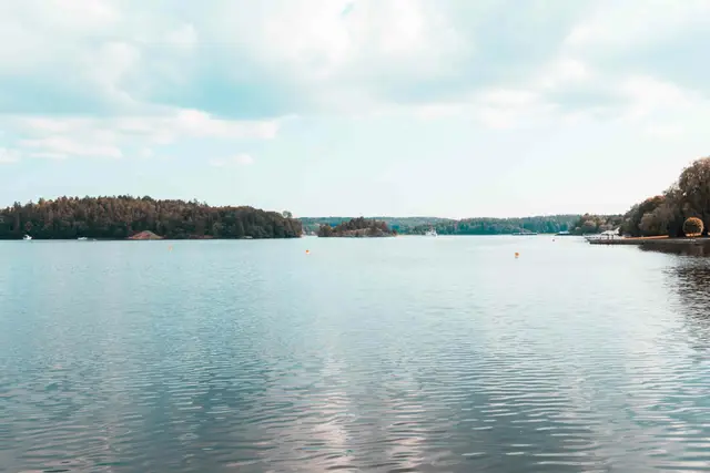Ruhige Wasserfläche mit bewaldeten Schäreninseln unter leicht bewölktem Himmel