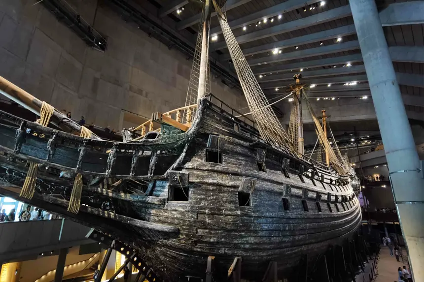 Der dunkle Rumpf des Kriegsschiffs Vasa mit Masten und Takelage in der Museumshalle