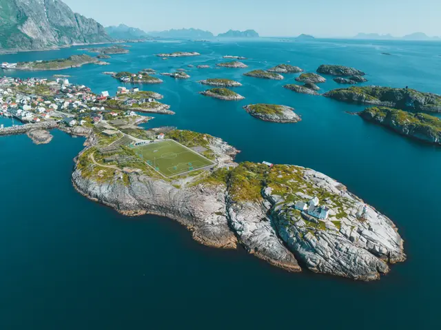 Henningsvær aus der Luft: Fußballplatz auf der Felsinsel zwischen türkisblauem Meer