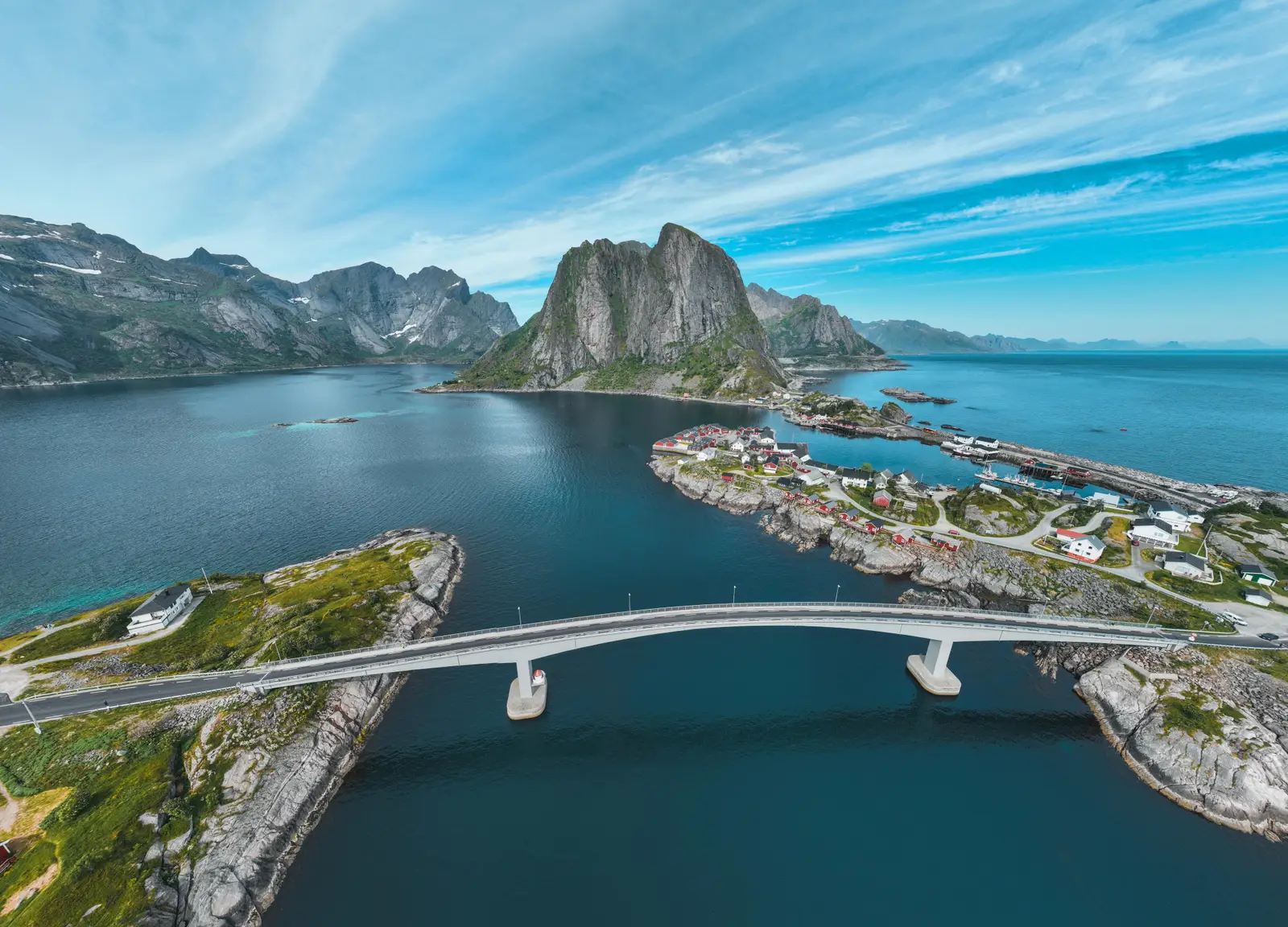 Unsere Drohnenaufnahme der Brücke nach Hamnøy mit Rorbuer-Dorf und steilen Felsgipfeln auf den Lofoten