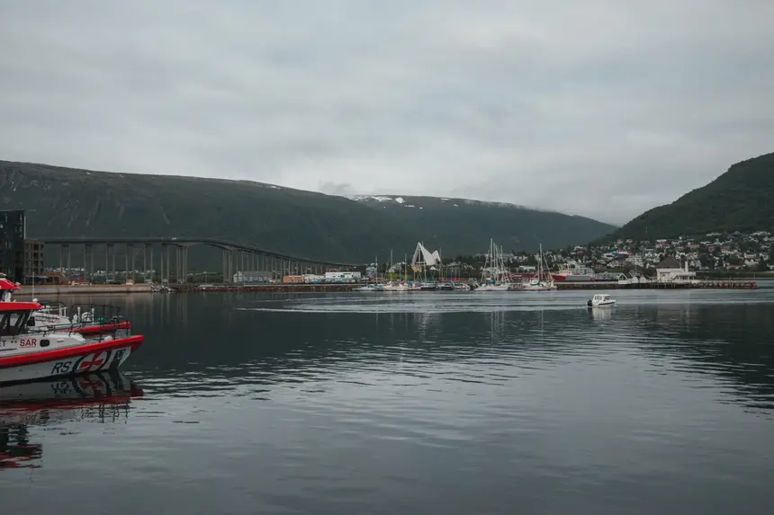 Tromsøs Hafen mit Brücke und Eismeerkathedrale unter grauem Himmel