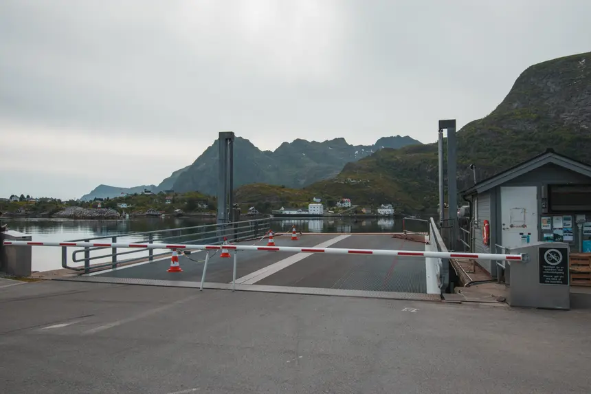 Fähranleger von Moskenes mit Schranke und Pylonen vor grünen Bergen