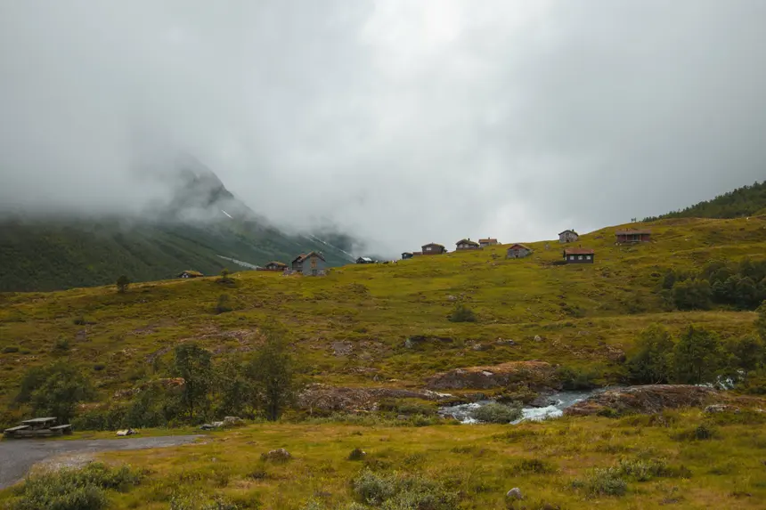 Verstreute Hütten auf grünen Almwiesen bei Byrkjelo unter tief hängenden Wolken