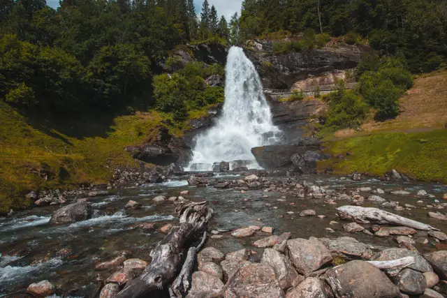 Der Steinsdalfossen stürzt über eine Felskante, davor ein steiniges Flussbett