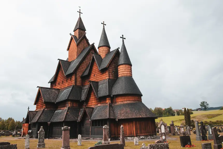 Dunkle Stabkirche Heddal mit gestaffelten Schindeldächern über dem alten Friedhof