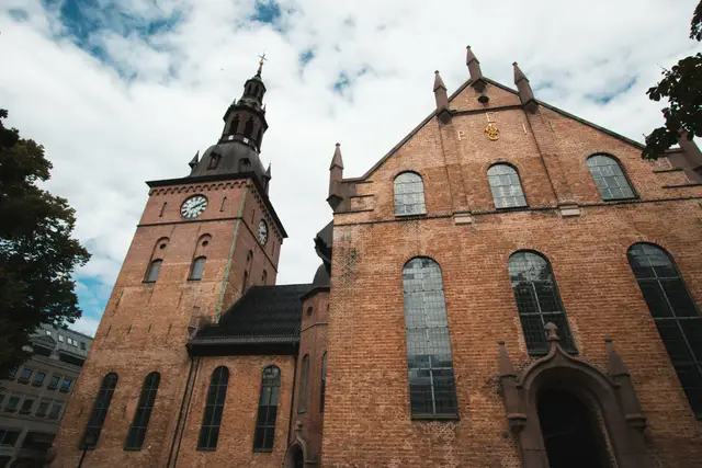 Historische Backsteinkirche mit Uhrturm und geschwungener Turmhaube unter Wolken