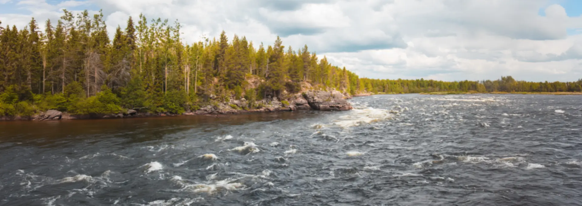 Rauschende Stromschnellen an einem bewaldeten Fluss in Finnland
