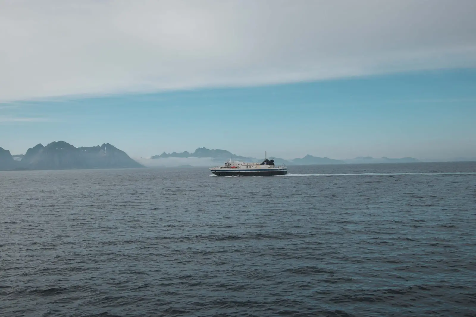 Die Autofähre von Moskenes nach Bodø auf dem Vestfjord, im Dunst dahinter die Bergkette der Lofoten