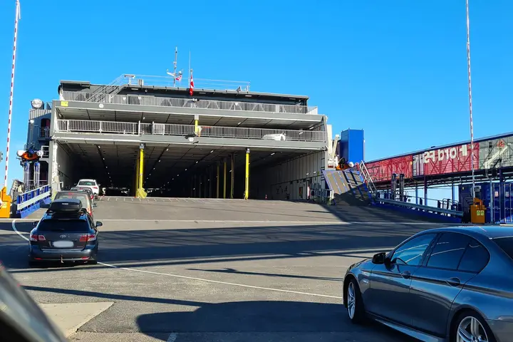 Wartende Autos vor der geöffneten Heckklappe einer großen Fähre am Terminal