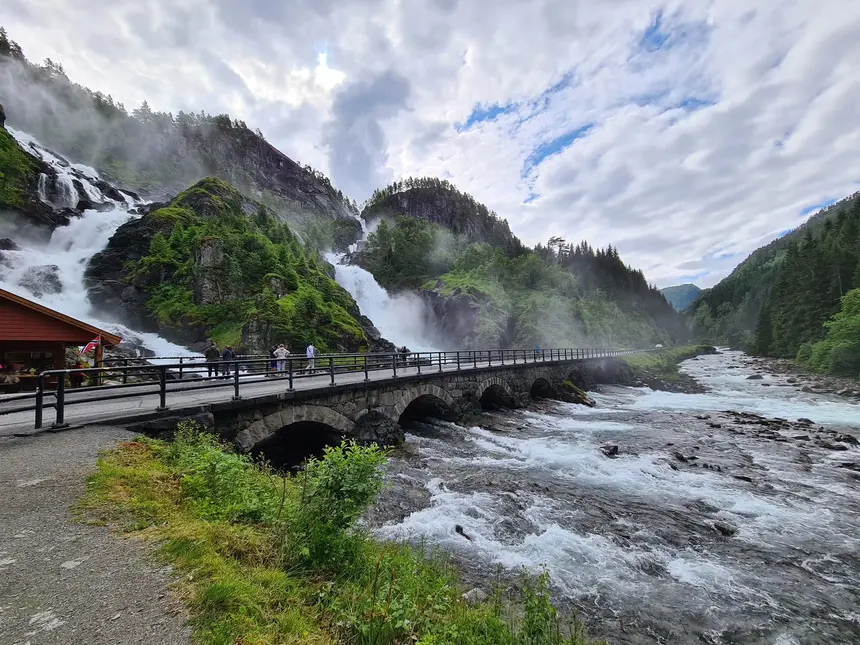 Der Låtefossen stürzt als Doppelwasserfall neben der alten Steinbogenbrücke herab