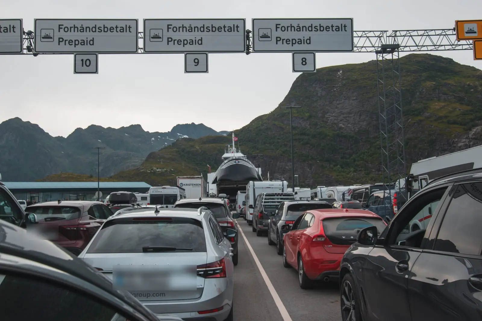 Fährspuren mit Prepaid-Schildern am Hafen von Moskenes, dahinter die Lofoten-Berge