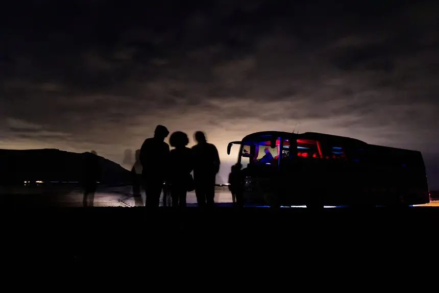 Kleine Gruppe als Silhouette neben einem Minibus in der Polarnacht