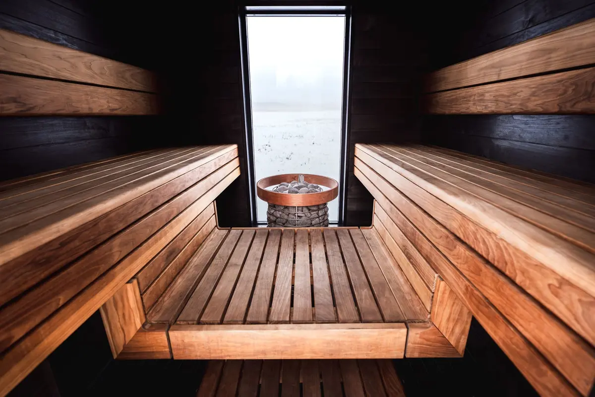 Holzbänke und Saunaofen in einer finnischen Sauna mit Blick nach draußen