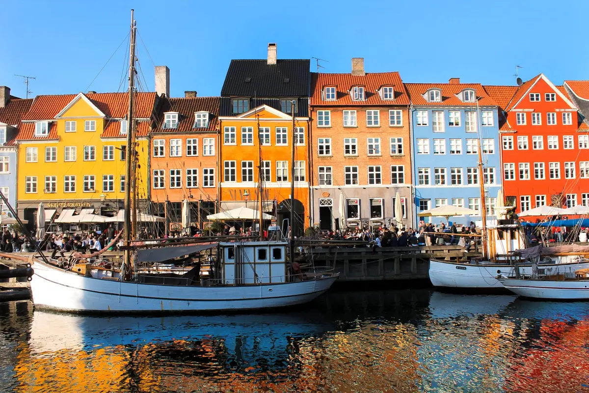 Bunte Häuserzeile und historische Segelboote am Nyhavn in Kopenhagen bei Sonnenschein