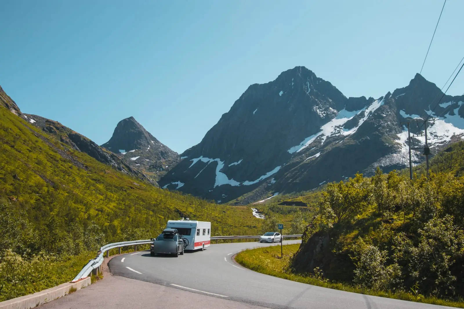 Gespann mit Wohnwagen unterwegs auf einer Bergstraße auf Senja