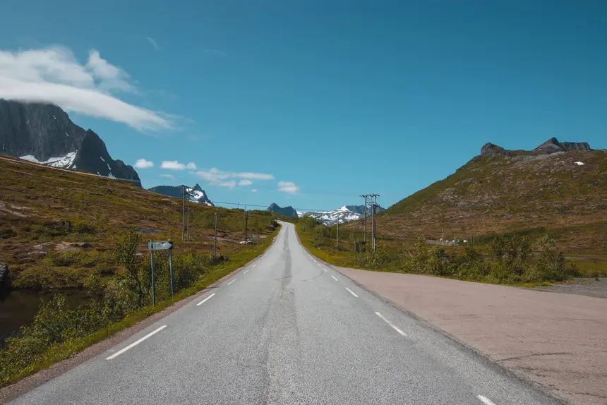 Leere Straße auf Senja führt direkt auf schneegefleckte Berge zu, kein Schiff kommt hierher