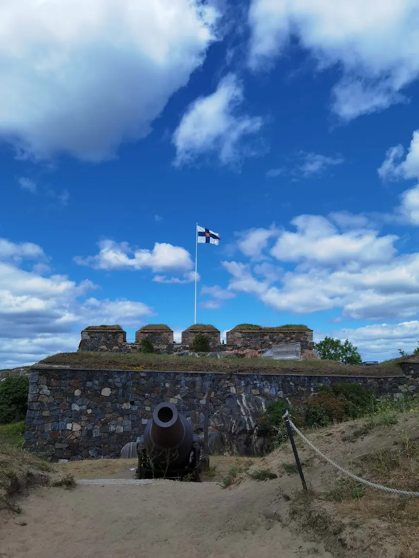 Historische Kanone vor der Festungsmauer von Suomenlinna mit finnischer Flagge