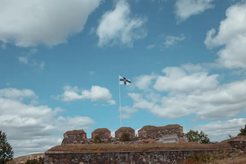 Die finnische Flagge weht über den grasbewachsenen Wällen von Suomenlinna, Helsinkis schönster Picknick-Terrasse