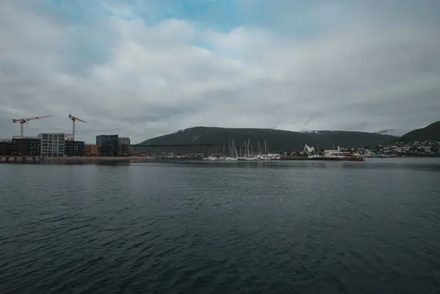 Hafen von Tromsø mit Brücke und Eismeerkathedrale unter grauem Himmel